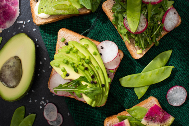 bovenaanzicht van vegetarische toastjes met verse groenten groene doek - Foto, afbeelding