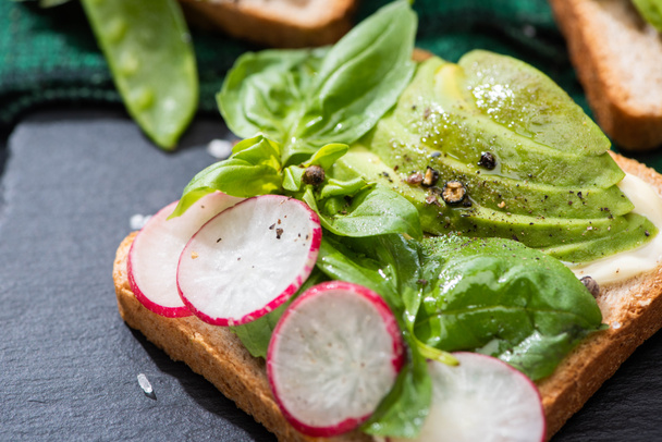 close up of healthy toasts with radish, basil and avocado on cloth - Foto, Imagem