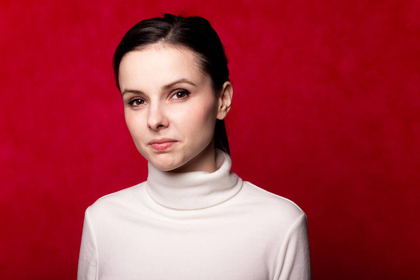 girl in a white turtleneck, portrait on a red background - Photo, Image