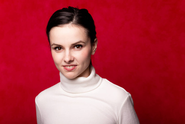 girl in a white turtleneck, portrait on a red background - Фото, изображение