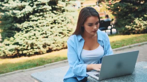 Attractive brunette girl student is using laptop in city center, being inspired by nature beauty. Close up. Copy space. 4K. - Záběry, video