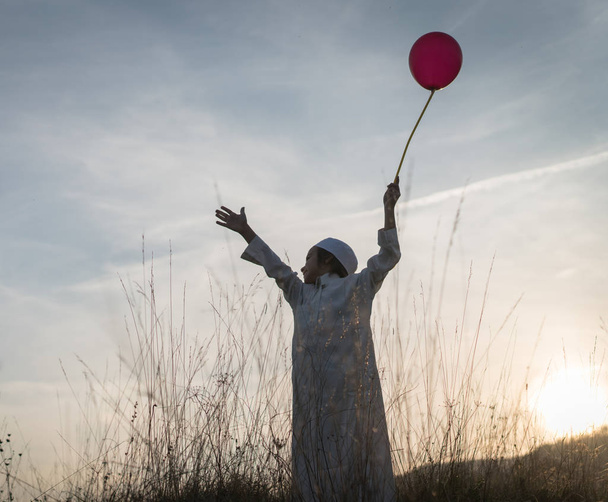 Muslim little child on grass meadow with balloon - Foto, afbeelding