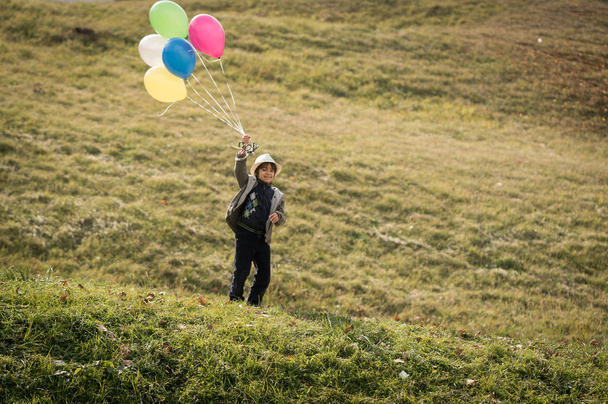 Маленький милый мальчик на травяном лугу с воздушными шарами
 - Фото, изображение