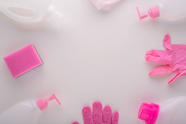 вид зверху біло-рожеві засоби очищення гумові рукавички, губка, пластикові пляшки для прибирання будинку на білому тлі
 - Фото, зображення
