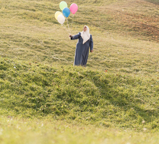 Donna musulmana con palloncini su prato erboso verde - Foto, immagini