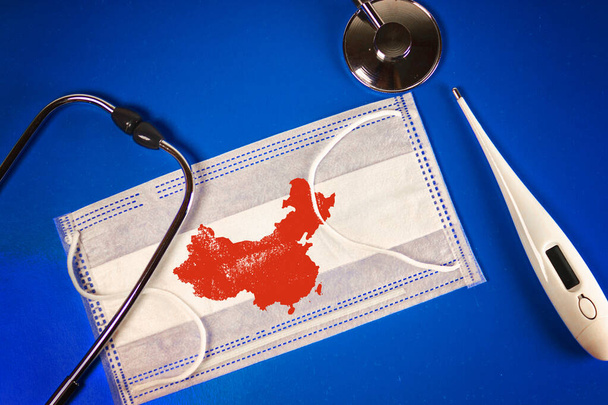Stethoscope, thermometer and thermometer medical mask with People's Republic of China map country silhouette and a stamp: 2019-nCoV, on a blue background - Fotoğraf, Görsel
