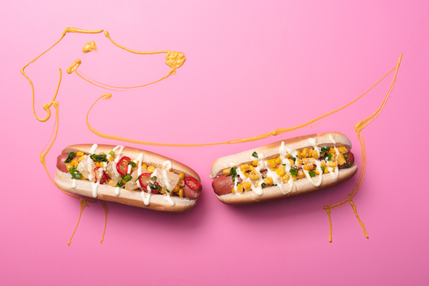 top view of two hot dogs on pink with dog drawn with mustard  - Photo, Image