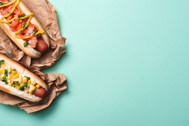 shora pohled na dva chutné hot dogy v papíře na modré - Fotografie, Obrázek
