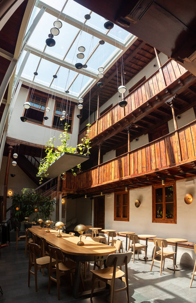 Чудовий сучасний інтер "єр кафе з стильними меблями у внутрішньому дворі старого будинку з дерев" яними балконами. - Фото, зображення