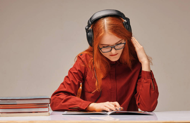 red-haired female student in headphones she is learning - Foto, immagini
