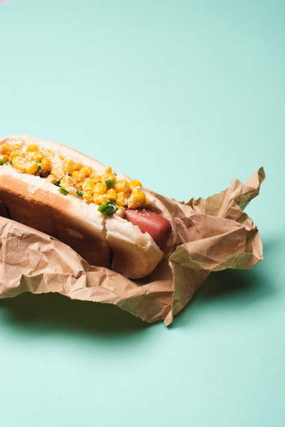 yummy hot dog with corn in paper on blue - Фото, изображение