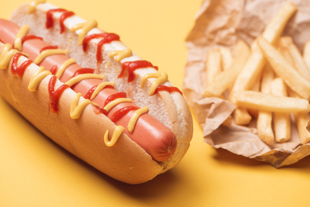 delicioso cachorro-quente insalubre e batatas fritas em papel em amarelo
  - Foto, Imagem