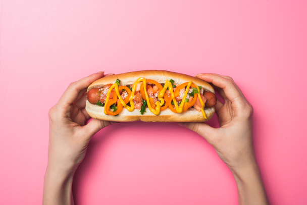 cropped view of woman holding yummy hot dog with mustard on pink - Photo, Image