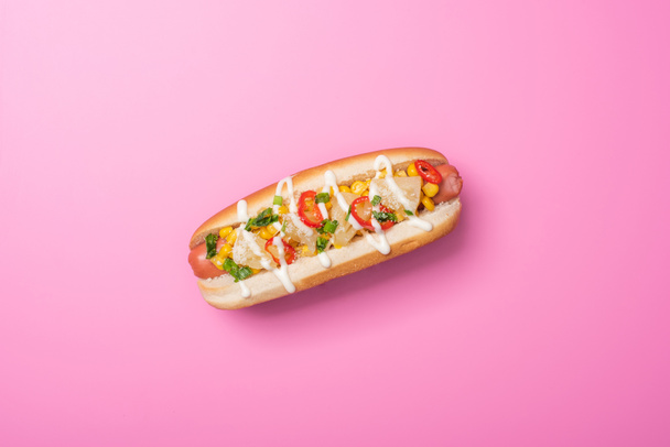 top view of one tasty hot dog in bun on pink - Foto, afbeelding