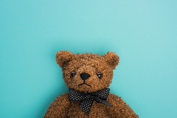 Top view of brown teddy bear with bow on blue background - Foto, afbeelding