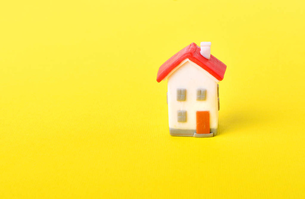 Dream about own habitation. Concept with miniature toy house with red roof on a yellow background.  - Fotó, kép