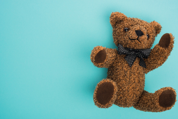 Draufsicht auf Teddybär mit Schleife auf blauem Hintergrund - Foto, Bild