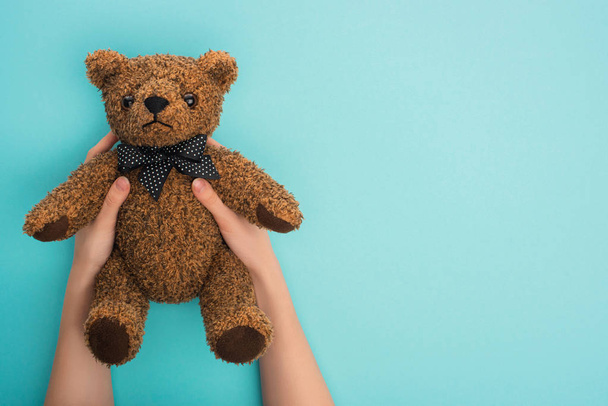 Cropped view of woman holding teddy bear on blue background - Foto, Bild