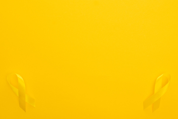 Widok z góry żółte wstążki na kolorowe tło, międzynarodowa koncepcja dzień nowotworu dzieciństwa - Zdjęcie, obraz