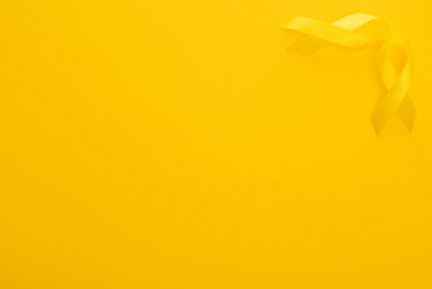 Visão superior de fitas de consciência amarela em fundo colorido brilhante, conceito de dia internacional do câncer infantil
  - Foto, Imagem