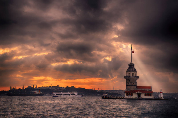 Panenská věž a istanbulská krajina za zamračeného dne s měnícími se světly. Maidenova věž nebo Kiz Kulesi se nachází uprostřed Bosporu, Istanbul v Turecku. - Fotografie, Obrázek