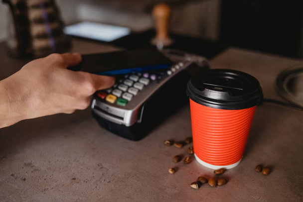 Customer pays for coffee using smartphone - Foto, afbeelding