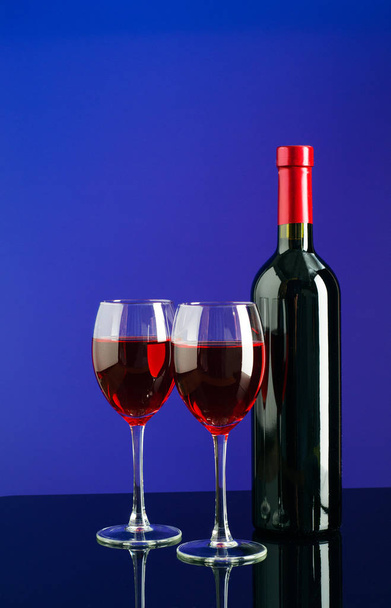 Glasses and bottle of wine on bright blue background - 写真・画像