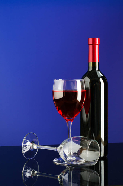 Glasses and bottle of wine on bright color background - 写真・画像