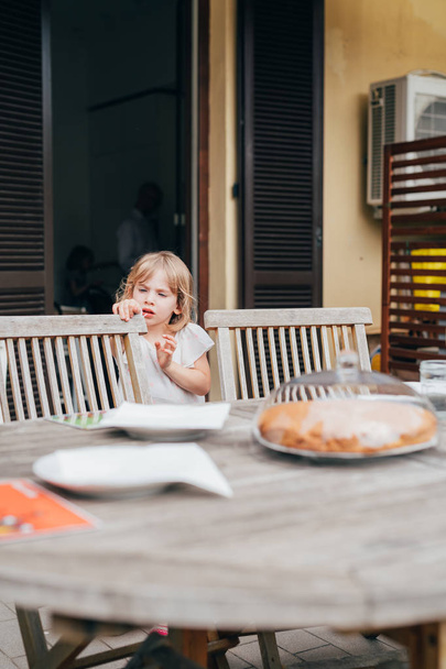 niña al aire libre casi sentada mesa para desayunar
  - Foto, imagen