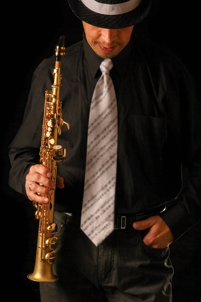 soprano saxophone in the hands of a guy on a black background - Photo, Image