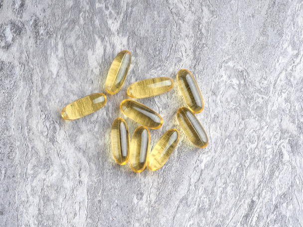 Πολλές κάψουλες Omega 3 σε ένα γκρι φόντο πέτρα. Έννοια υγειονομικής περίθαλψης - Φωτογραφία, εικόνα