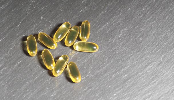 Many capsules Omega 3 on a gray stone background. Health care concept - Photo, Image