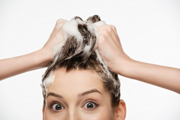здивована дівчина з широкими відкритими очима миє волосся ізольовано на білому
 - Фото, зображення