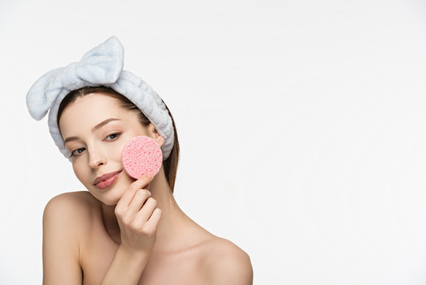 smiling girl holding cosmetic sponge near face isolated on white - 写真・画像