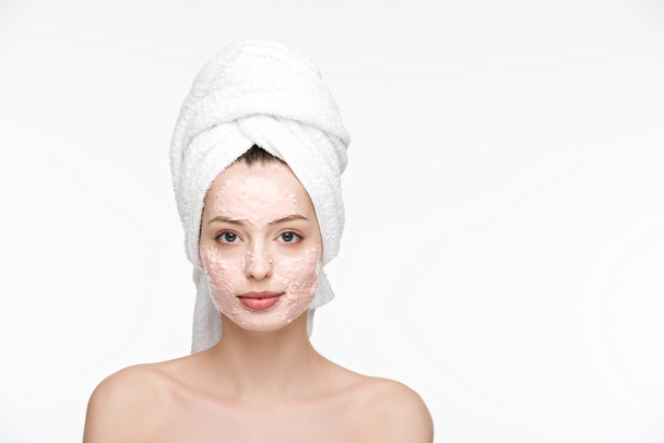 atrakcyjna dziewczyna z maską peeling na twarzy i ręcznik na głowie patrząc na aparat odizolowany na białym - Zdjęcie, obraz