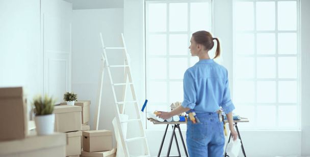 Happy woman paints wall with roller at home - Foto, afbeelding