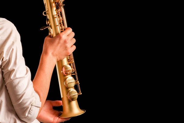 soprano saxophone in the hands of a girl on a black background - Φωτογραφία, εικόνα