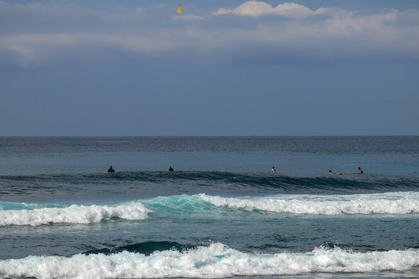 Junge Surfer sitzen auf Surfbrettern und warten auf die richtige Welle.  - Foto, Bild