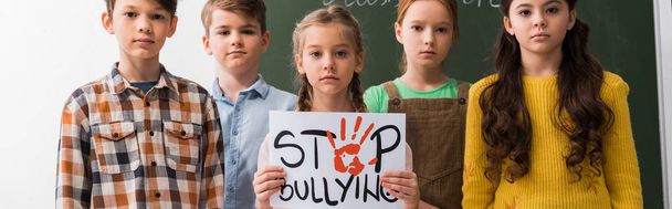 tiro panorâmico de escolares segurando cartaz com lettering stop bullying
  - Foto, Imagem
