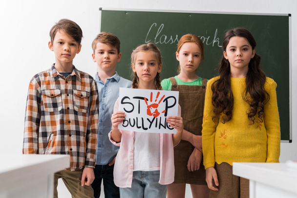 selective focus of schoolkids holding placard with stop bullying lettering  - Photo, Image