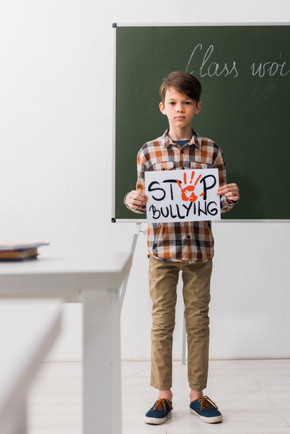 selective focus of schoolboy holding placard with stop bullying lettering  - Photo, Image