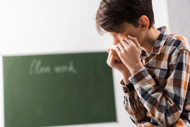 bullied and depressed schoolboy covering face in classroom  - Foto, Imagen
