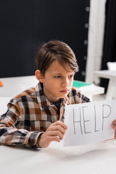 enfoque selectivo de los escolares deprimidos sosteniendo papel con letras de ayuda, concepto de bullying
 - Foto, Imagen