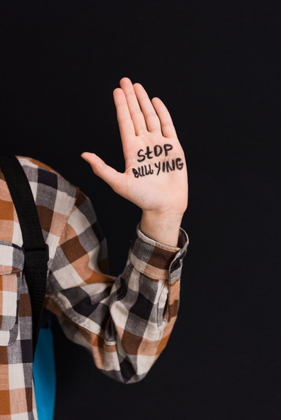 vista ritagliata di scolaro con stop bullismo lettering a portata di mano isolato su nero
  - Foto, immagini