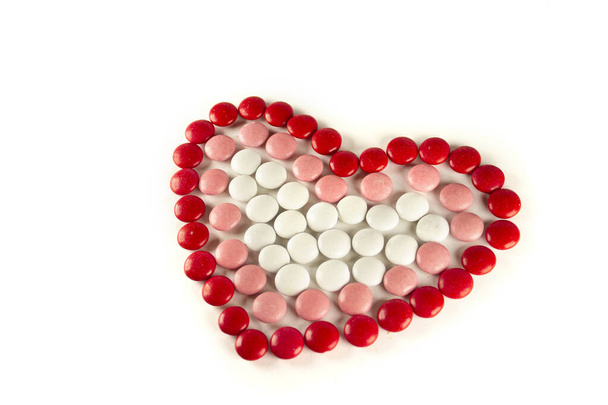 Colorful dragee beans in the shape of a heart on a white background. Decoration background. Closeup - Fotó, kép