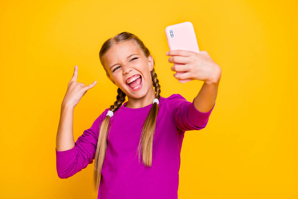 Close-up portrait of her she nice attractive cool glad ecstatic cheerful cheery girl taking selfie showing horn having fun sign isolated over bright vivid shine vibrant yellow color background - Foto, Imagem