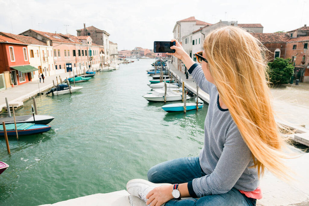 Молода жінка, яка користується телефоном на мосту в Мурано (Венеція). - Фото, зображення