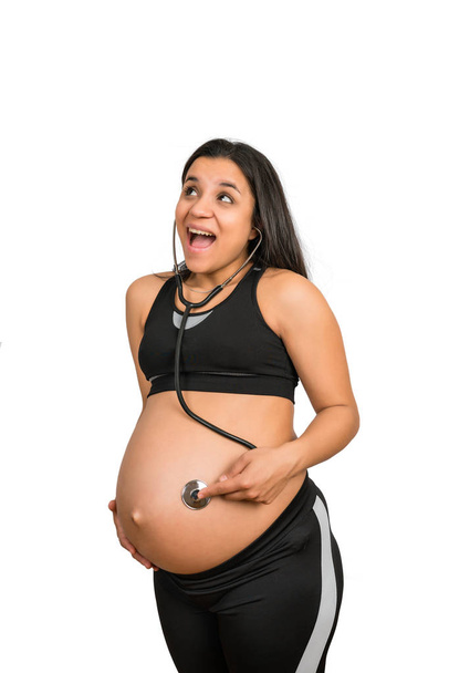Schwangere mit Stethoskop am Bauch hört dem Baby zu.. - Foto, Bild