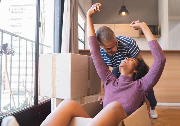 Latin couple having fun with cardboard boxes in new house. - Photo, Image