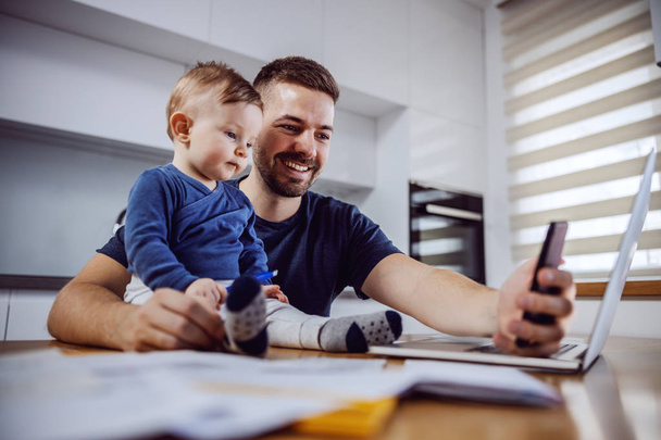 Genç gülümseyen baba yemek masasında oturan biricik oğluyla selfie çekiyor. Aile değerleri kavramı. - Fotoğraf, Görsel